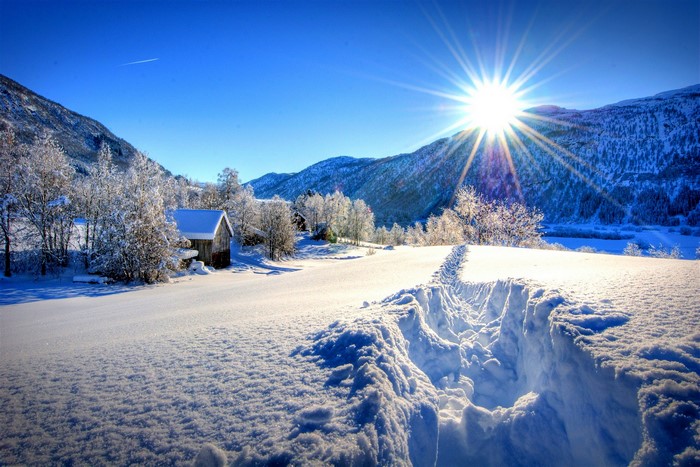 Winter landscape with snow-covered mountains and a sunlit path