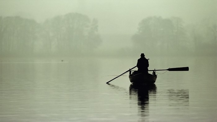 Person rowing a boat on a foggy lake