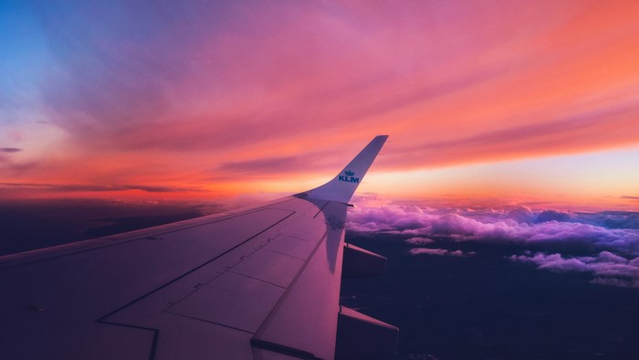 KLM airplane wing at sunset over clouds