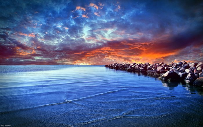 Dramatic sunset over the ocean with a rocky shore