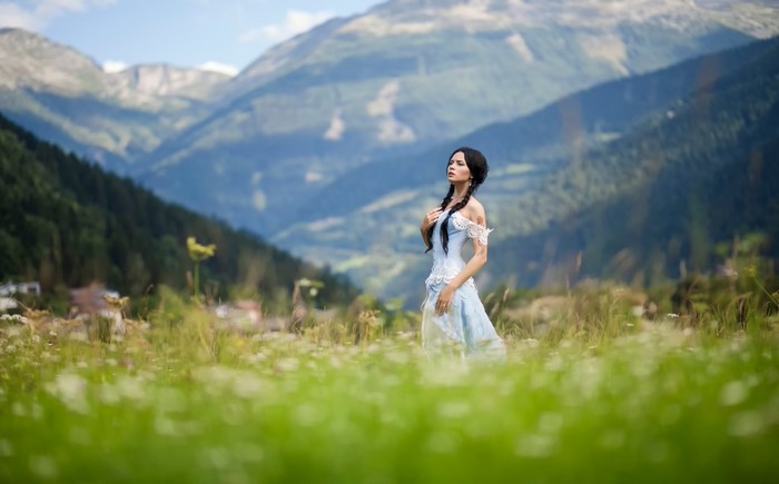 Woman in a blue dress in a mountain meadow