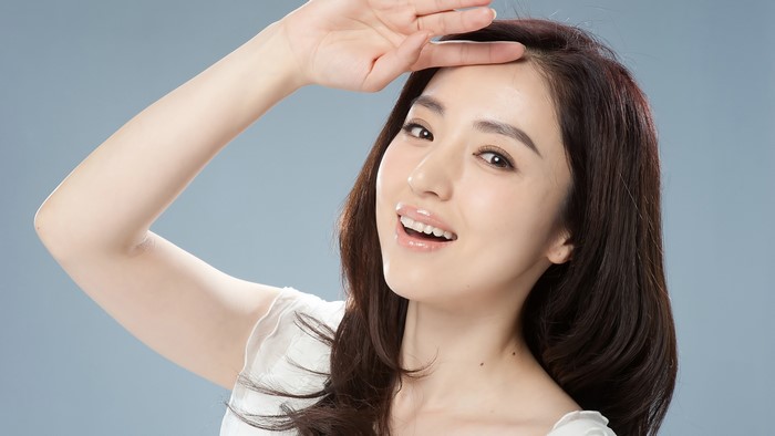 Asian woman smiling with hand on forehead