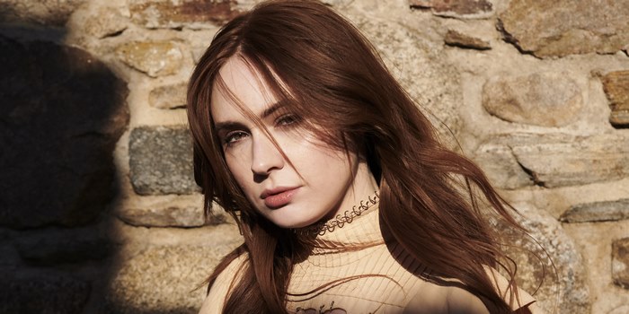 Karen Gillan posing in front of a stone wall