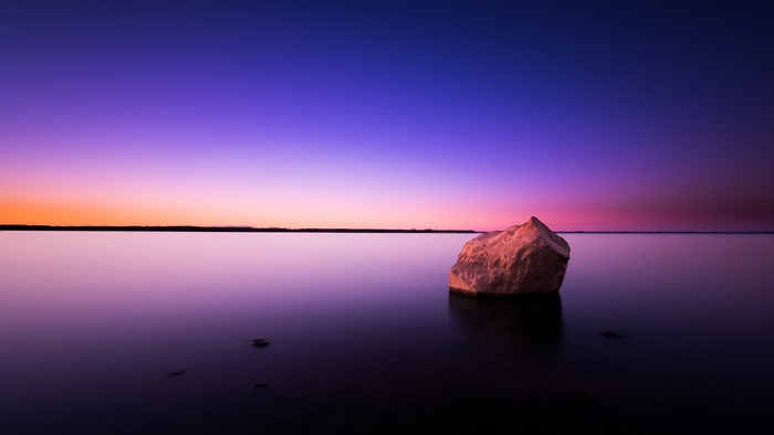 Rock in calm water at sunset