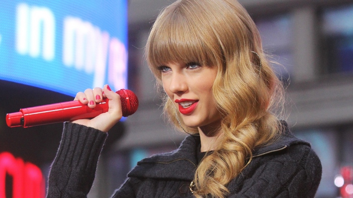 Taylor Swift singing with a red microphone