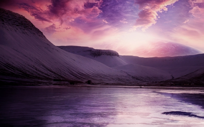 Snowy mountains and frozen lake under a pink sky
