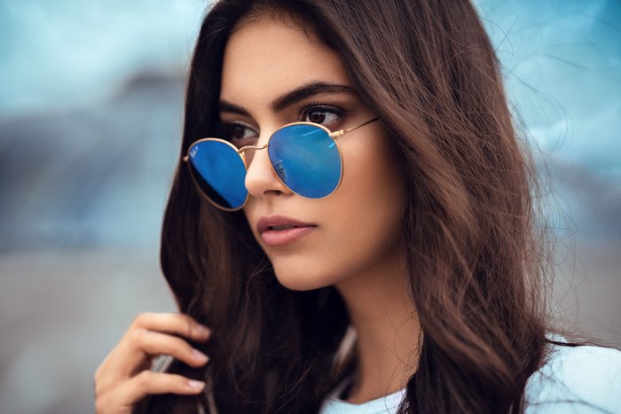 Woman with long brown hair and blue sunglasses