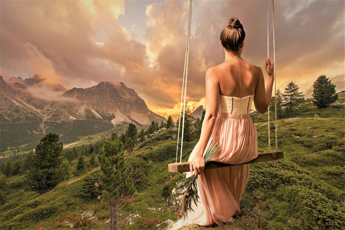 Woman on a swing in the mountains at sunset