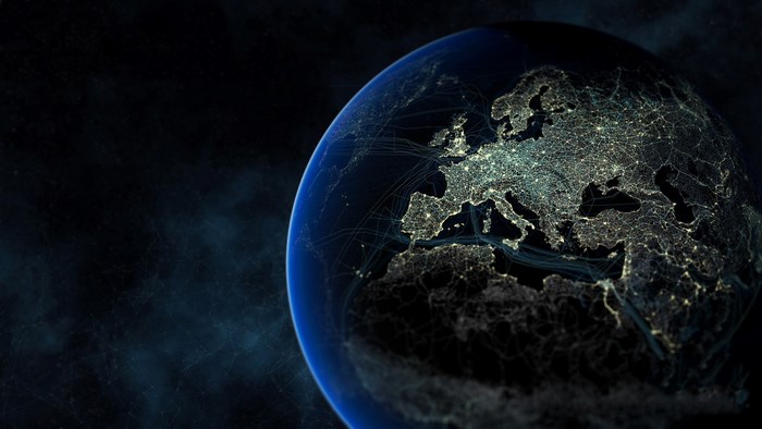 Earth at night with glowing cities and flight paths