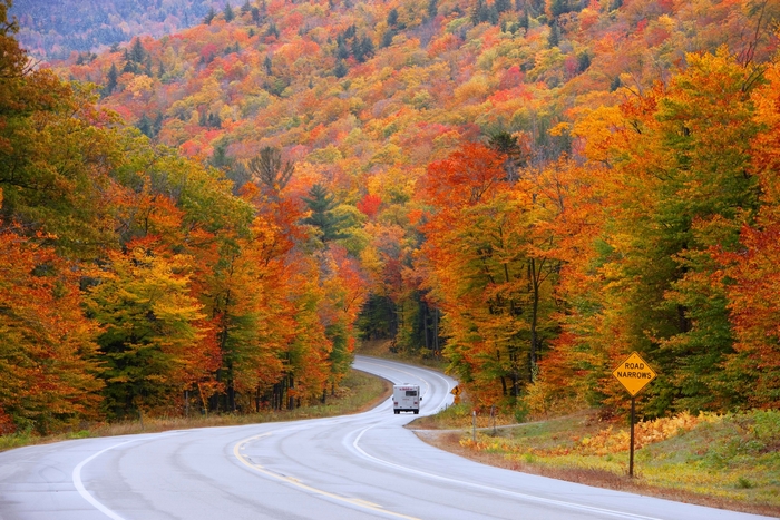 RV driving on a winding road through autumn forest