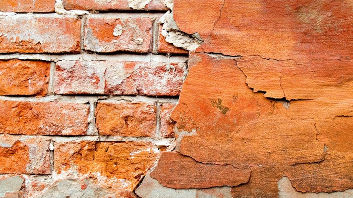 Cracked orange plaster over brick wall texture