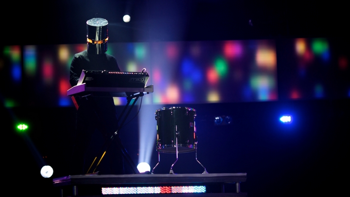 Musician in helmet playing keyboard on stage
