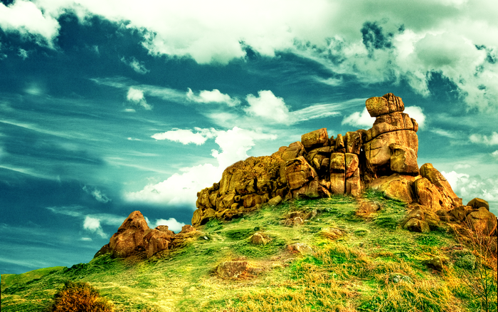 Rocky outcrop on a grassy hill under a cloudy sky