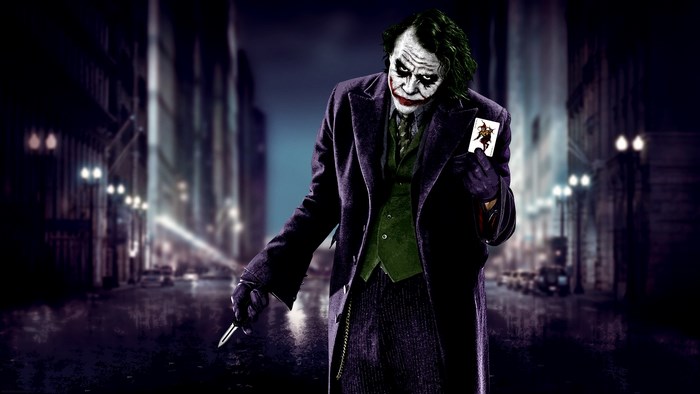 The Joker holding a playing card in a city street