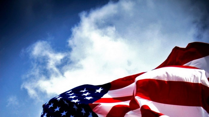 American flag waving against a cloudy blue sky