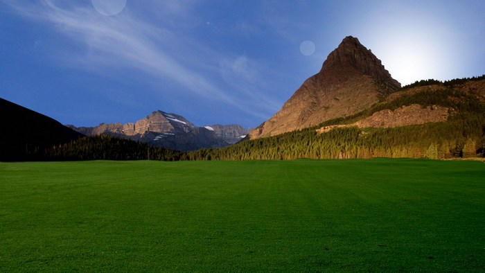 Mountain landscape with green field and blue sky