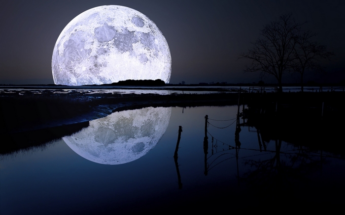 Giant moon reflecting on water at night