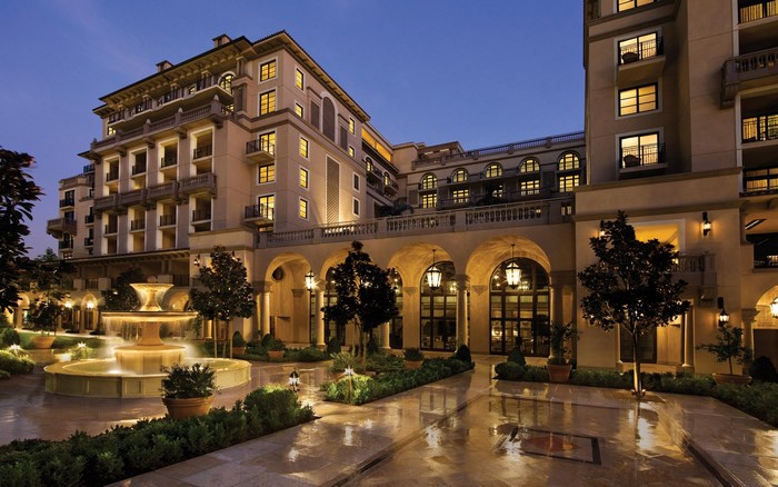 Hotel courtyard with fountain and arched walkway at dusk