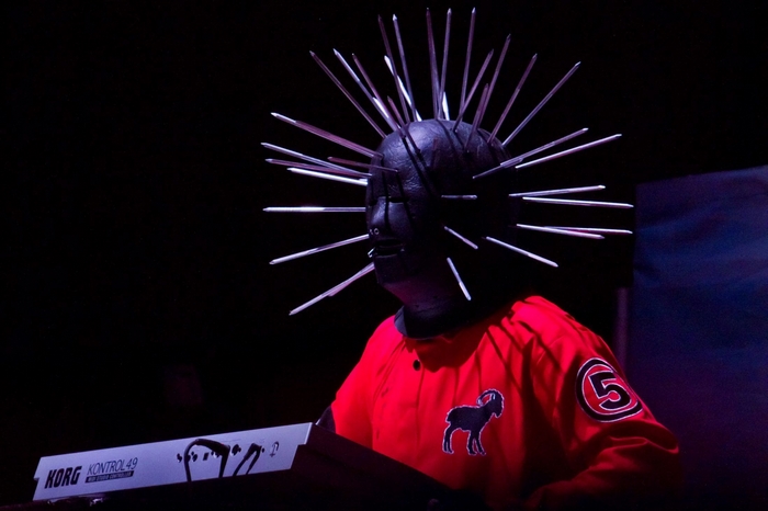 Slipknot member with spiked mask and red uniform