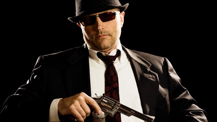 Gangster in a suit and hat holding a gun