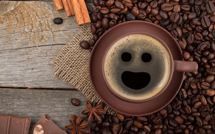 Coffee cup with smiley face on coffee beans