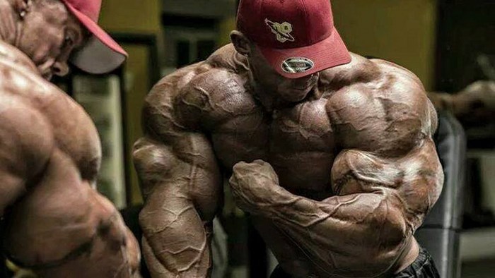 Bodybuilder flexing in red cap