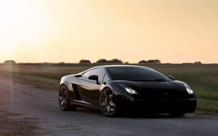 Black Lamborghini Gallardo on a dirt road at sunset