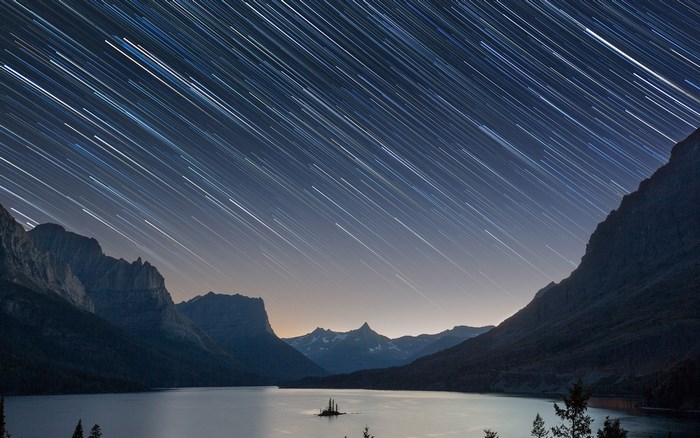 Star trails over a lake and mountains