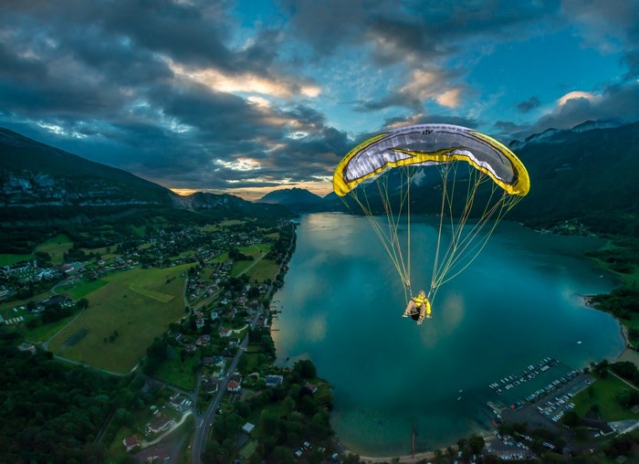Paraglider over a lake and mountains at dusk