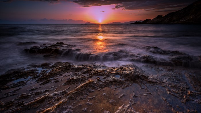 Sunset over rocky coast with ocean waves