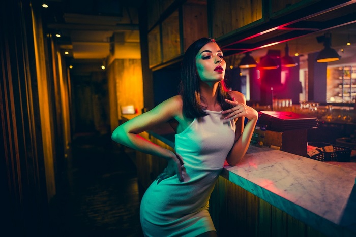 Stylish Woman Posing by Bar Counter with Neon Lights