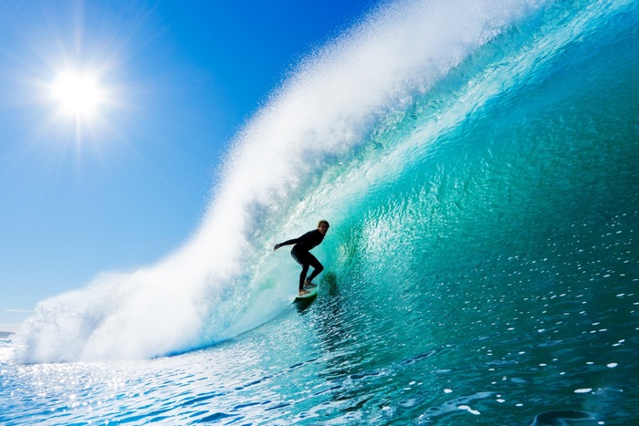 Surfer riding a large wave under the sun