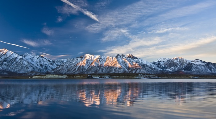 Snow-capped mountains reflected in a lake at sunset