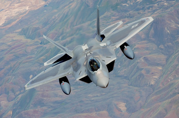 F-22 Raptor fighter jet flying over mountains