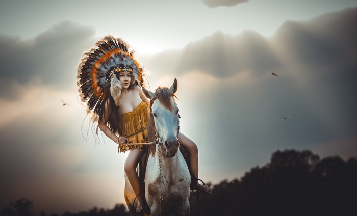 Girl in Feather Headdress on White Horse at Sunset