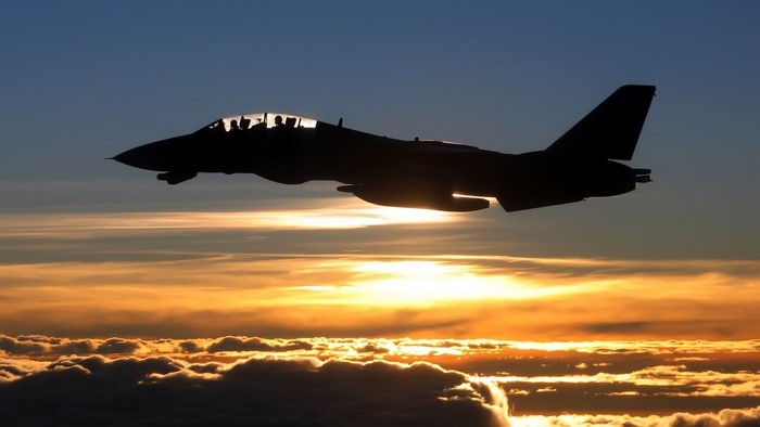Silhouette of Grumman F-14 Tomcat flying at sunset