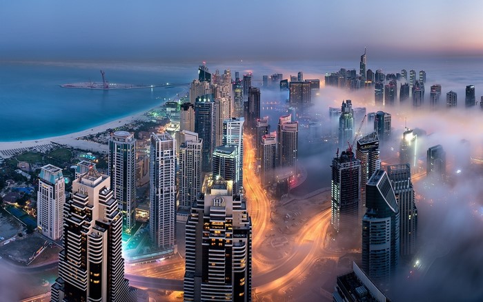 Dubai skyscrapers shrouded in mist at sunrise over the sea