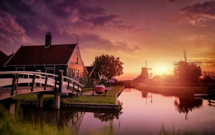 Sunset over canal with windmills and houses in Zaanse Schans, Netherlands