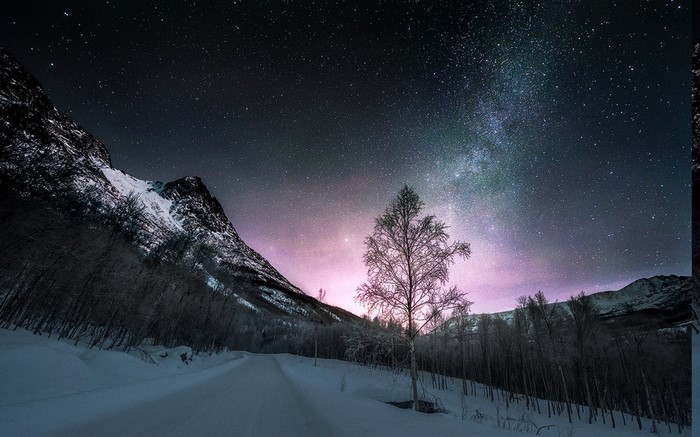 Winter road under starry night sky in Norway