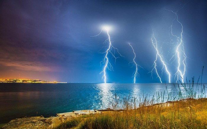 Lightning Storm Over Coastal City at Night