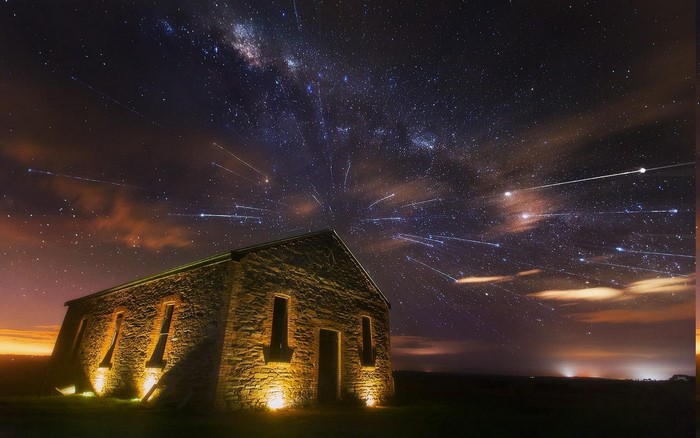 Stone building under the Milky Way and meteor shower