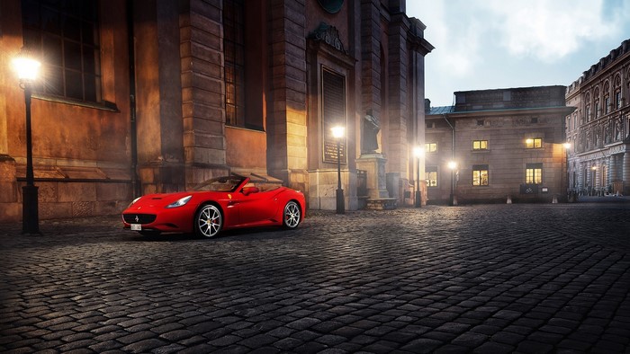 Red Ferrari California convertible on cobblestone street