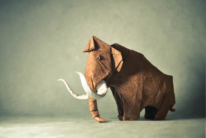 Brown origami mammoth with white tusks