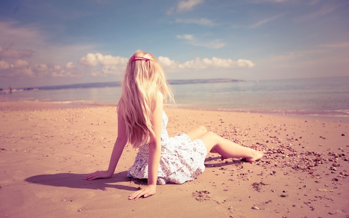 Woman with long blonde hair sitting on a beach