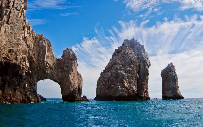 Arch rock formation in the ocean under a blue sky