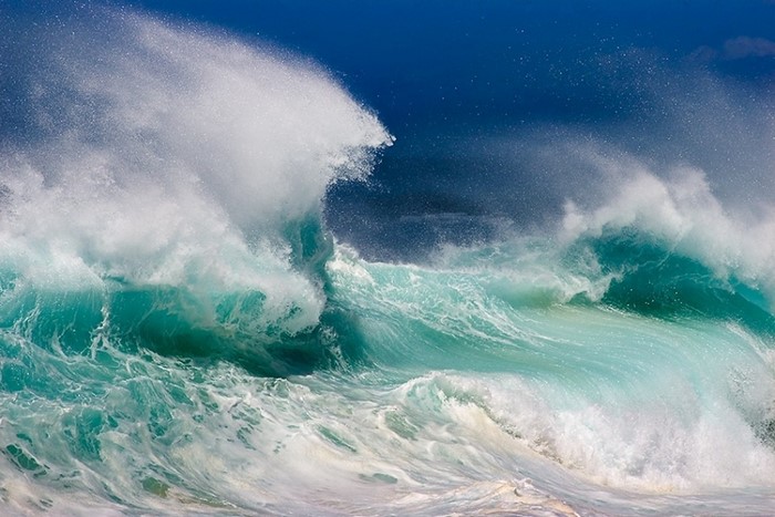 Powerful ocean waves crashing under a blue sky