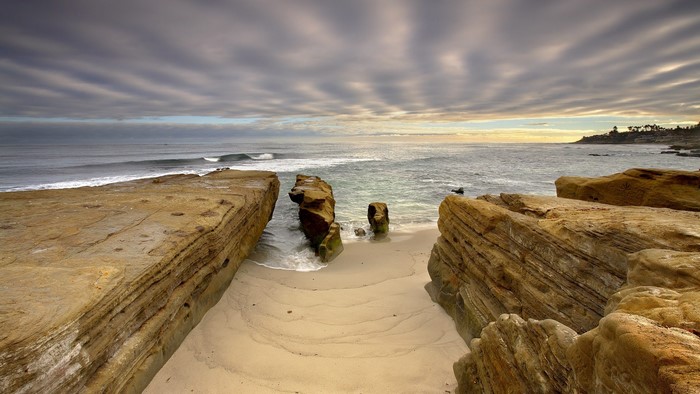 Rocky Coastline with Waves and Cloudy Sky