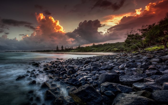 Sunset over rocky beach with dramatic clouds