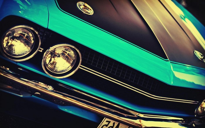 Close-up of a vintage turquoise American muscle car grille and headlights