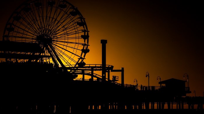 Ferris wheel and roller coaster on a pier at sunset